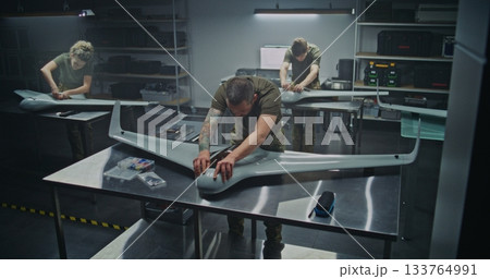 Woman and Men Assembling Advanced Military Drones in Factory 133764991