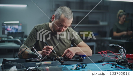 Worker With Tattoo on Arm Soldering Internal Electronics Onto Contemporary Drone Frame Worker With Tattoo on Arm Soldering Internal Electronics Onto Contemporary Drone Frame 133765018