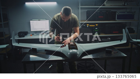 Woman and Two Men Collaboratively Assemble Unmanned Aerial Vehicle 133765065
