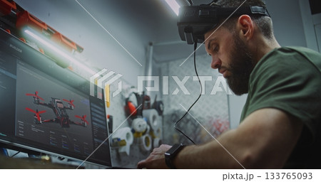 Bearded Man in Tactical Gear Deeply Focused, Using Computer Display and FPV Gear 133765093
