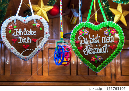 Festive german gingerbread hearts with loving messages at a christmas market. Two traditional german lebkuchenherzen decorated with colorful icing 133765105