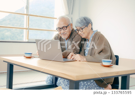 旅館の和室でパソコンとスマホを使うシニア夫婦 旅館の和室でパソコンとスマホを使うシニア夫婦 133765595