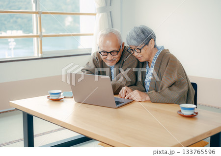 旅館の和室でパソコンとスマホを使うシニア夫婦 133765596