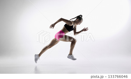 Female sprinter captured in dynamic mid-stride on white background 133766046