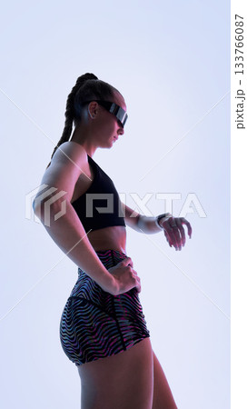 Futuristic athlete standing in confident pose with smart visor and gradient light Futuristic athlete standing in confident pose with smart visor and gradient light 133766087