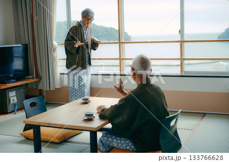 窓辺で手を振る高齢女性と見守る夫の旅館シーン 133766628