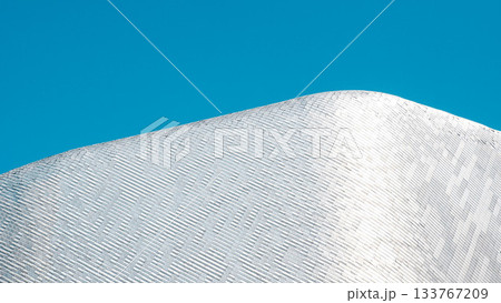 Minimalist Abstract Architecture: Curved White Facade Against Bright Blue Sky 133767209