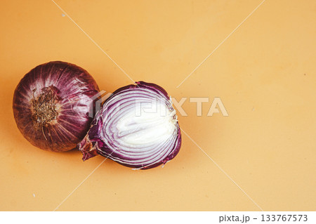 Close-up of sliced and whole red onions on orange background Close-up of sliced and whole red onions on orange background 133767573