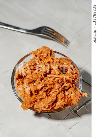 a bowl of shredded pulled pork with a metal fork 133768835