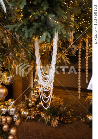 Festive holiday decor with gold ornaments and pearl garland Festive holiday decor with gold ornaments and pearl garland 133769153