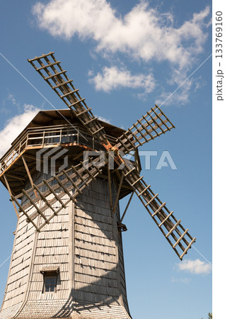 Historic wooden windmill against blue sky with clouds Historic wooden windmill against blue sky with clouds 133769160