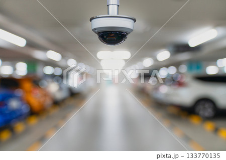 CCTV security camera in underground parking garage with blurred cars and soft lighting 133770135