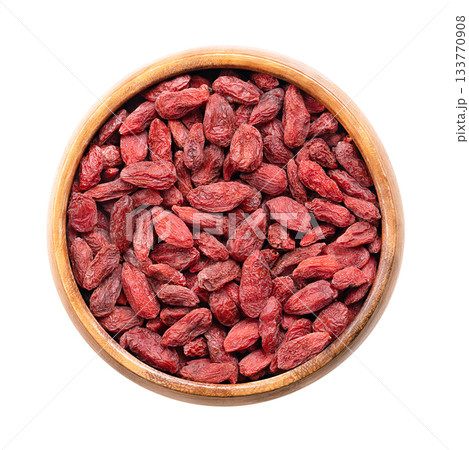 Dried goji berries, in a wooden bowl. Also known as Chinese wolfberry, red medlar, and matrimony vine. Bright orange-red sweet fruits of the shrub Lycium barbarum, native to China and across Asia. 133770908