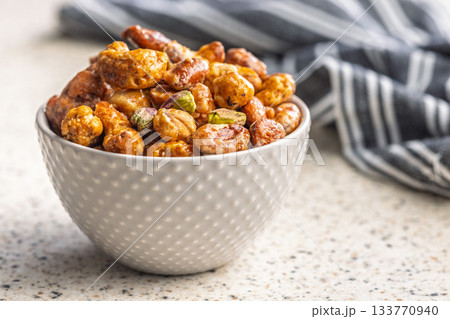 Nuts coated in sugar glaze in bowl on kitchen table. Nuts coated in sugar glaze in bowl on kitchen table. 133770940