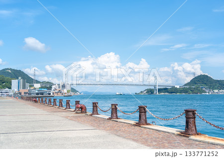 関門海峡と関門橋を望む下関の海沿い遊歩道と夏の青空 133771252
