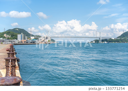 関門海峡と関門橋を望む下関の海沿い遊歩道と夏の青空 133771254