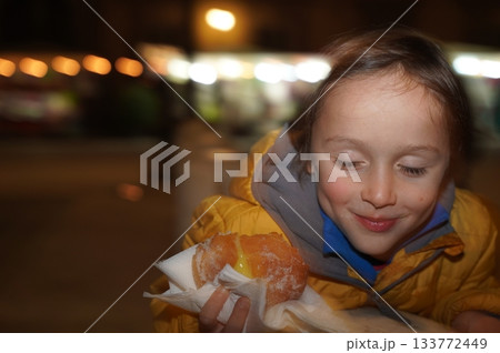 Child Enjoys Sweet Pastry at Night Market 133772449