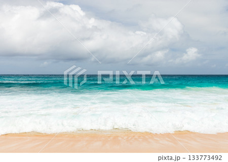 A pristine beach scene featuring turquoise sea, white surf and warm sand 133773492