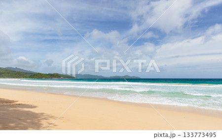 A serene beach scene featuring golden sand, turquoise waters, and gentle waves 133773495