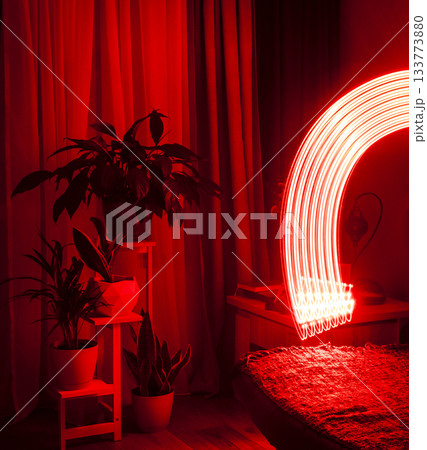 A long-exposure photograph that captures the pathway of a moving red light source in a dimly lit room A long-exposure photograph that captures the pathway of a moving red light source in a dimly lit room 133773880