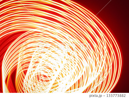 A long-exposure photograph that captures the pathway of a moving red light source in a dimly lit room 133773882