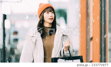 雪が降る冬の街でショッピングをする女性 133773977
