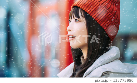 雪の降る冬の街角に立つ笑顔の女性 133773980