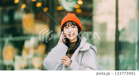 冬の街角でスマートフォンを使う笑顔の女性 133773981