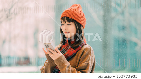 冬の街角でスマートフォンを使う笑顔の女性 133773983
