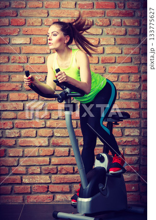 Active woman using exercise bike at the gym. Active woman using exercise bike at the gym. 133775627