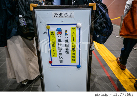 フェリー乗船手続きを案内する日本語の告知看板と待機する乗客 フェリー乗船手続きを案内する日本語の告知看板と待機する乗客 133775665