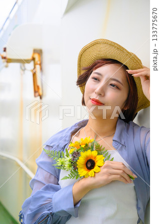 麦わら帽子をかぶりヒマワリを持つ若い女性のポートレート 麦わら帽子をかぶりヒマワリを持つ若い女性のポートレート 133775670