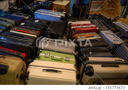 床に無造作に積み上げられた多数のスーツケースとキャリーバッグ 133775673
