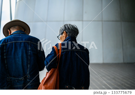 デニムジャケットを着た高齢のカップルが歩く、モダンな建物の内部 133775679