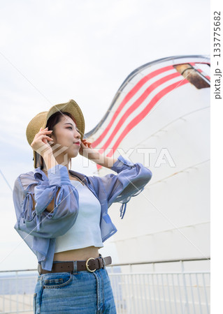 麦わら帽子をかぶった若い女性が船の上で空を見上げる 133775682