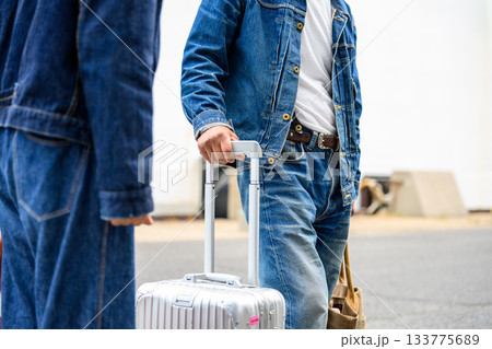 デニムジャケットとジーンズ姿の男性がスーツケースを持つ旅行の様子 デニムジャケットとジーンズ姿の男性がスーツケースを持つ旅行の様子 133775689