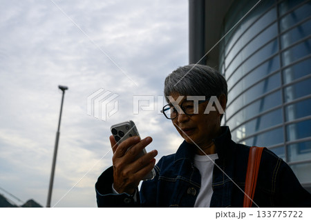 スマートフォンを見る眼鏡をかけた白髪の中年男性のポートレート 133775722