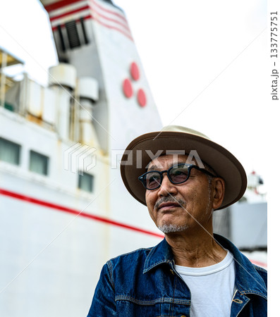 フェリーを背景に佇む麦わら帽子をかぶった中高年の日本人男性 133775751