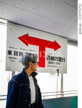 駅の案内表示板の前で矢印の方向を見つめる白髪の男性 駅の案内表示板の前で矢印の方向を見つめる白髪の男性 133775752
