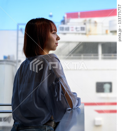 船の窓際で外を見つめる若い女性 船の窓際で外を見つめる若い女性 133775757