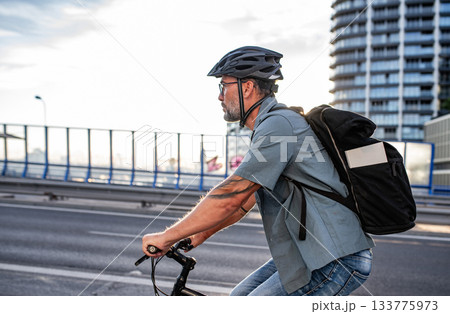 Male cyclist riding bike down the street. 133775973