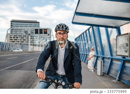 City commuter riding bike to office, wearing backpack and helmet. 133775995