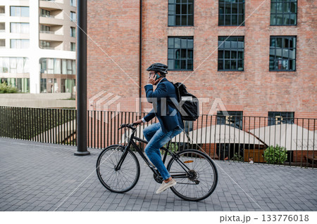City commuter riding bike to office, wearing backpack and helmet. City commuter riding bike to office, wearing backpack and helmet. 133776018