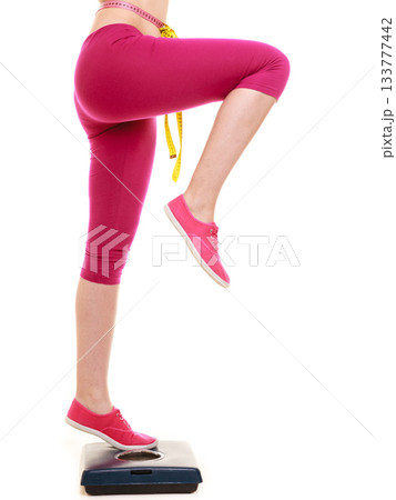 Woman with tape measure on weighing scale. Woman with tape measure on weighing scale. 133777442