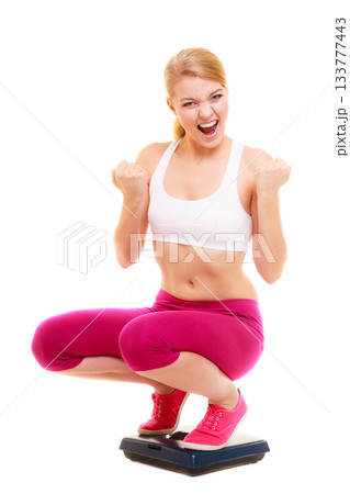Happy successful woman weighing scale. Dieting. 133777443