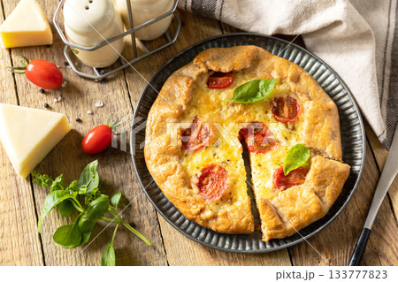 Crispy tomato galette with adyghe cheese and herbs on rustic background. 133777823