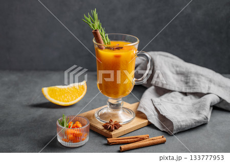 Sea buckthorn herbal tea in a glass on a wooden board on a dark background with orange Sea buckthorn herbal tea in a glass on a wooden board on a dark background with orange 133777953