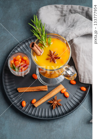 Sea buckthorn herbal tea in a glass on a black plate on a dark background with berries 133777954