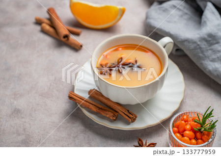 Sea buckthorn herbal tea in a cup on a light background with orange, spices and berries 133777959