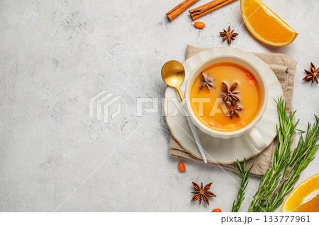 Sea buckthorn herbal tea in a cup on a light background with orange, herb, spices and berries. Sea buckthorn herbal tea in a cup on a light background with orange, herb, spices and berries. 133777961